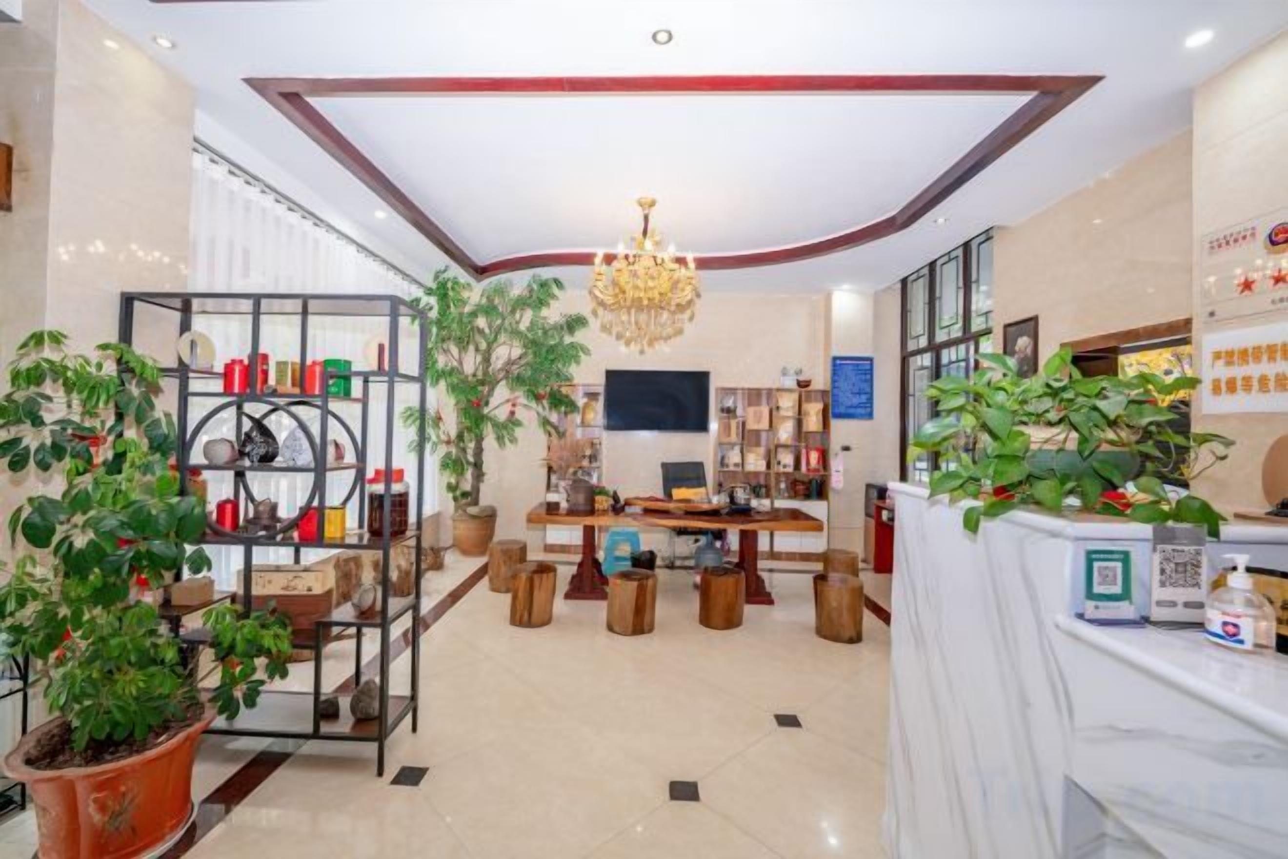 A hotel lobby with a reception desk, seating area, and a chandelier.