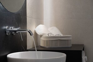 Ein Badezimmer mit weißem Waschbecken, schwarzer Wand und Handtuchhalter mit Handtüchern.