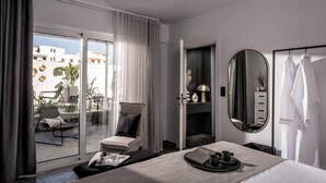 A modern hotel room with a large sliding glass door to a balcony, a comfortable seating area, a vanity with a mirror, and a neatly made bed. - Icos City 1 a modern apartment centrally located in Hersonissos (Limenas Chersonisou)