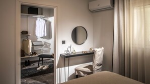 A hotel room with a bed, a desk with a chair, a mirror, a wardrobe, and an air conditioning unit. - Icos City 1 a modern apartment centrally located in Hersonissos (Limenas Chersonisou)