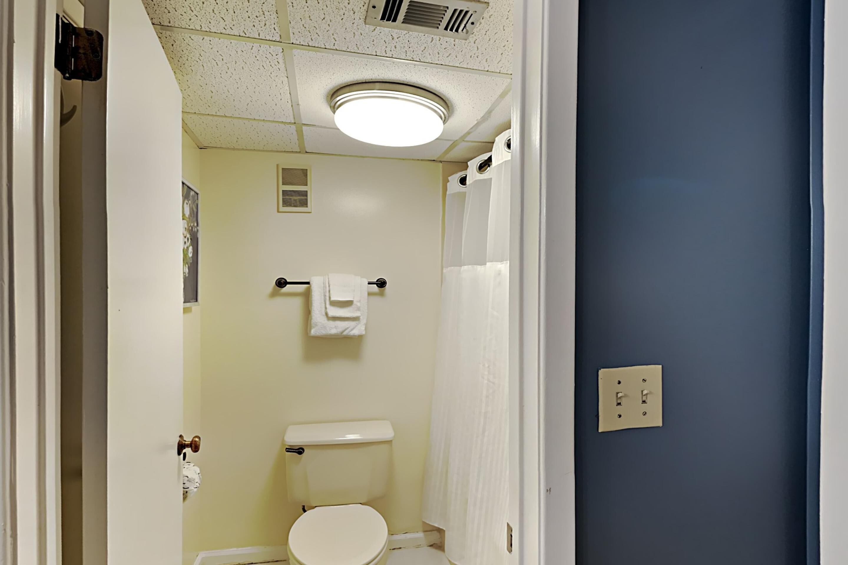 A bathroom with a toilet, a towel rack, and a shower curtain.