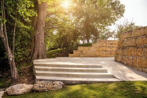 A set of concrete steps leading up to a stone wall, surrounded by trees and grass. - Cation on the Guadalupe (New Braunfels)
