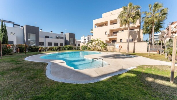 A swimming pool surrounded by a well-maintained lawn, with modern buildings in the background. - Modernly designed holiday flat in Mijas Costa (La Cala de Mijas)