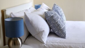 A neatly made bed with white linens, a blue lamp, and patterned pillows. - Swan Cove Gourock 1 bedroom apartment (Gourock)