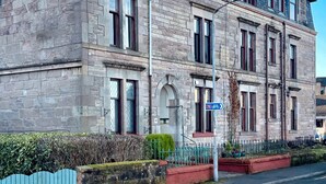 A two-story stone building with multiple windows and a visible entrance. - Swan Cove Gourock 1 bedroom apartment (Gourock)