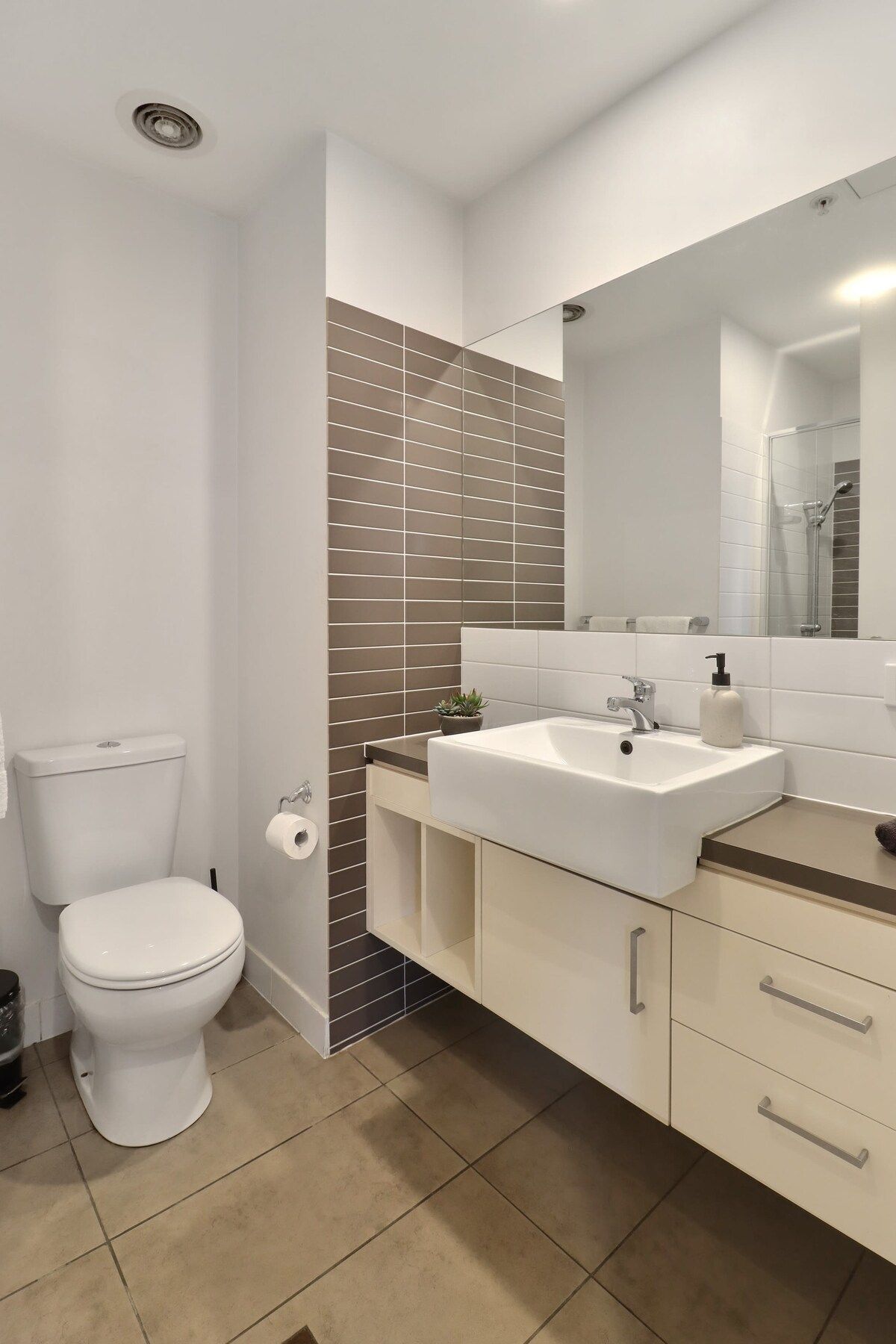 A modern bathroom with a toilet, sink, and mirror.