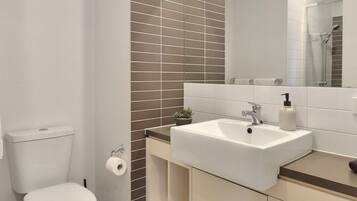 A modern bathroom with a toilet, sink, and mirror.