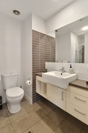 Un baño moderno con inodoro, lavabo y espejo.