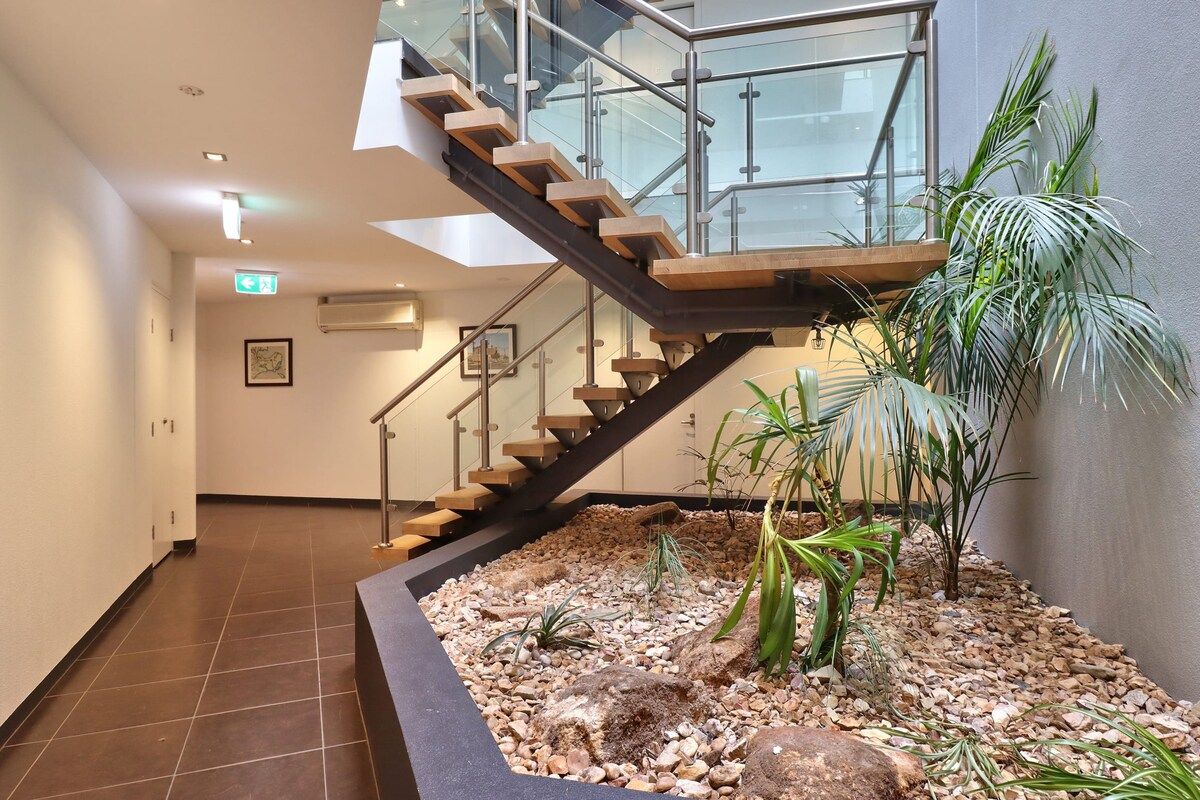 Un intérieur moderne avec un escalier, un bac à plantes et un sol carrelé.
