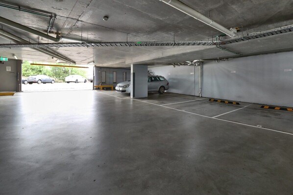 A multi-level parking garage with concrete floors and walls, featuring several parking spaces and a visible exit.
