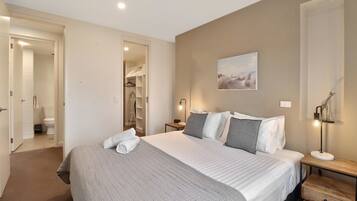 A bedroom with a bed, bedside tables, a wardrobe, and a painting on the wall.