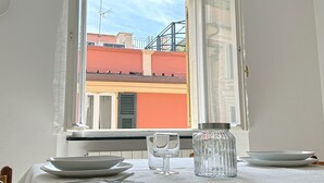 A dining table with plates, a glass, and a pitcher, set near a window with a view of buildings.