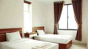 A hotel room with two single beds, a wooden headboard, a nightstand with a phone, and a window with curtains. - Call Sea Nha Trang  (Nam Nha Trang)