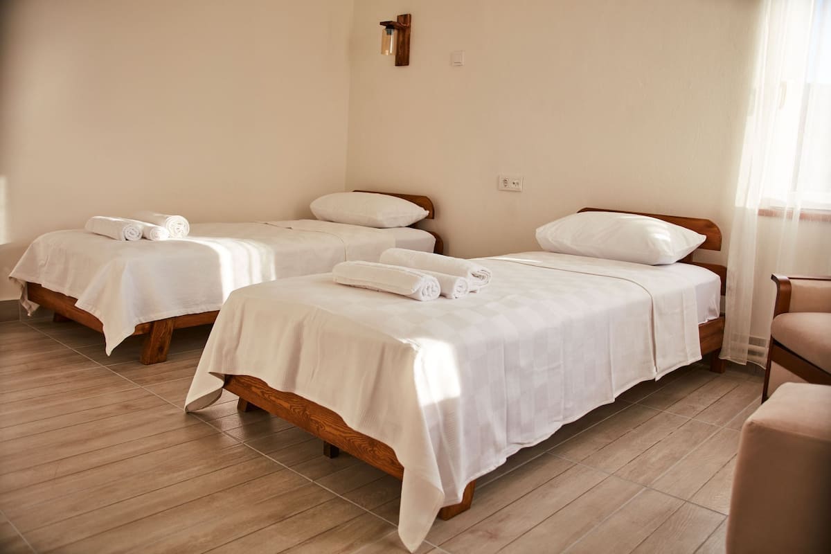 Ein Hotelzimmer mit zwei Einzelbetten, jeweils mit Holzrahmen und weißer Bettwäsche.