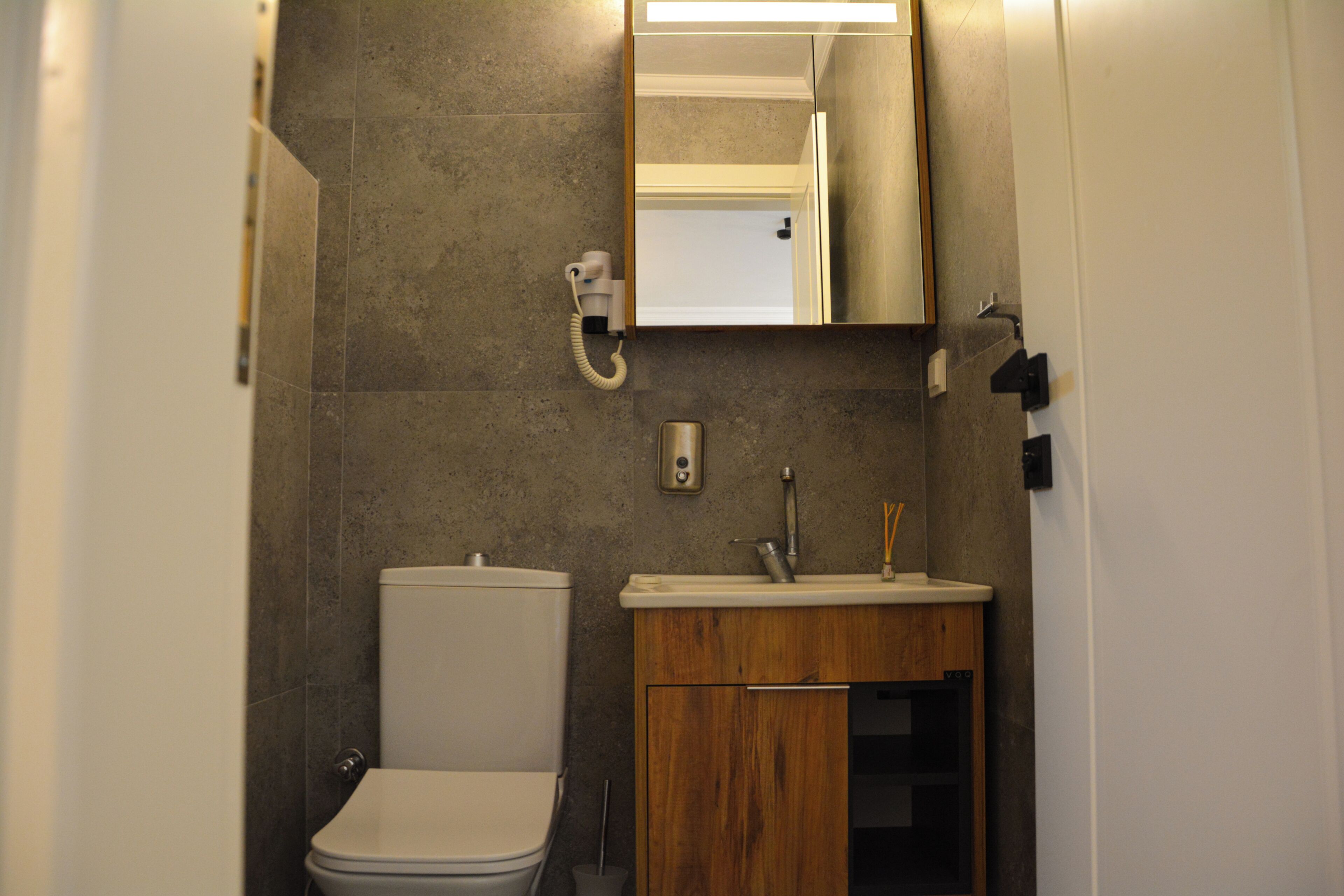 Un baño con inodoro, lavamanos, espejo y barra para toallas.