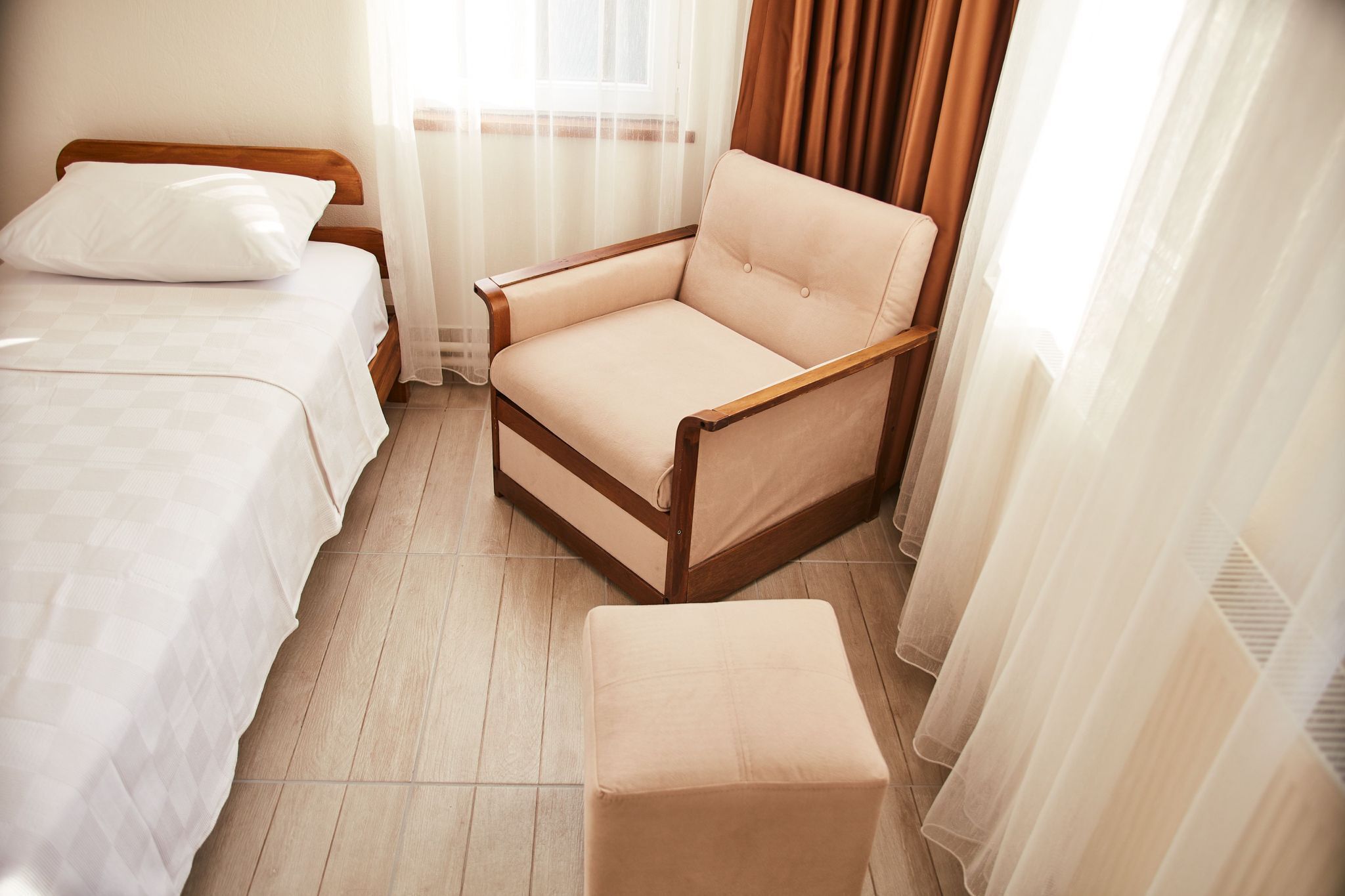 A bedroom with a bed, a chair, and an ottoman.