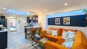 A modern living room with a sofa, a coffee table, and a kitchen in the background. - All Ensuite,smarttvs,garden,20 Mins to Nec,parking (Coventry)
