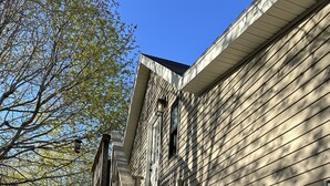 En trætrap fører op til et hus med et plankeværk i forgrunden.