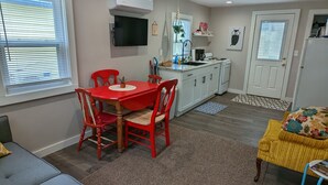 A compact living space with a dining area, kitchenette, and seating area. - Little Yellow Cottages #3 (Port Austin)