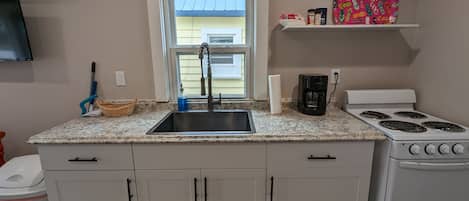 Enjoy cooking in this well-equipped kitchen with a granite countertop, stainless steel sink, and four-burner gas stove.