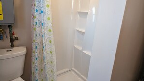 A bathroom with a toilet, shower, and a white sink. - Little Yellow Cottages #3 (Port Austin)