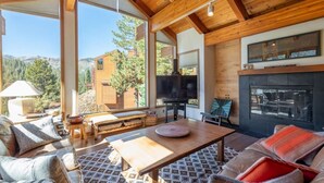 A spacious living room with a large TV, wooden furniture, and a fireplace.