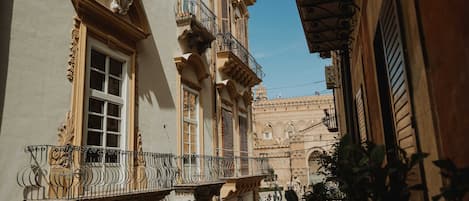 Una calle estrecha con balcones ornamentales y un cielo azul despejado.