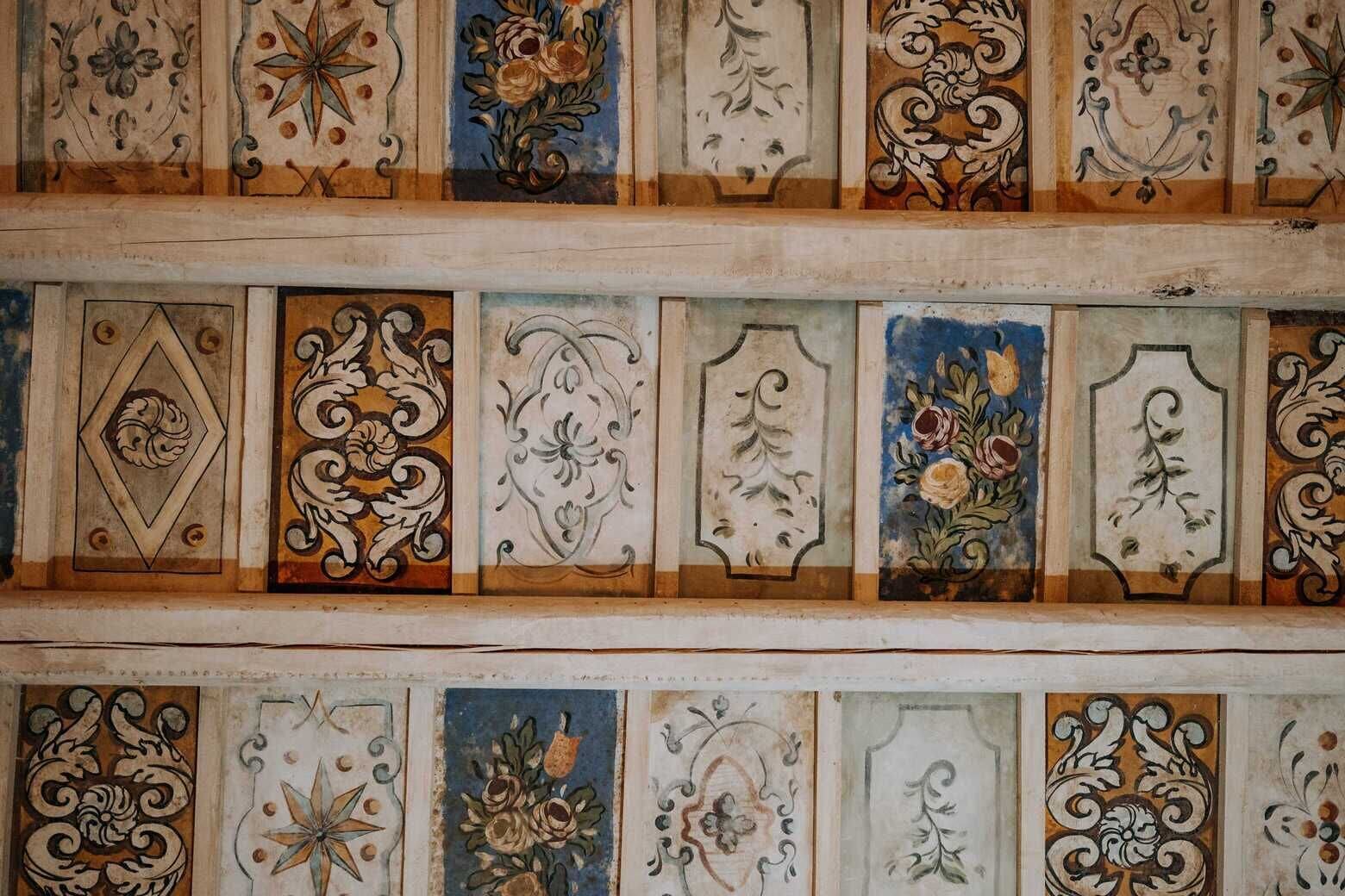A ceiling with decorative panels featuring floral and geometric patterns.