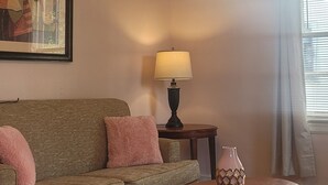 Uma sala de estar com ventilador de teto, sofá, mesa de centro, abajur e um vaso.