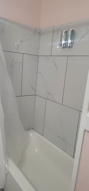 Bathroom features a white bathtub and shower area with a sleek, modern design.