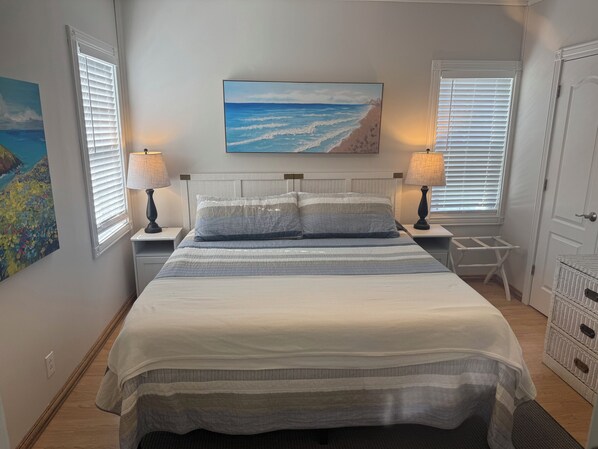 A bedroom with a bed, two bedside tables, a nightstand, a painting, and a door. - Large Beach House! 4 King beds! Great location! (South Haven)