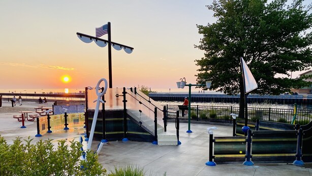 Un parque con equipo de ejercicio, una bandera y vistas al atardecer.