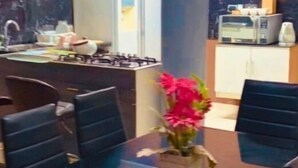 A dining area with a glass table and black chairs, a kitchen in the background, and a potted plant on the table. - 3 bedroom apartment in los olivos (Los Olivos)