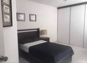 Une chambre à coucher avec un lit, une table de chevet, une lampe et une armoire.