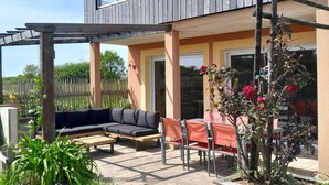 Una casa moderna de dos pisos con un patio cubierto, mobiliario exterior y un jardín.