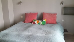 Una cama con una colcha azul claro y dos almohadas rojas.