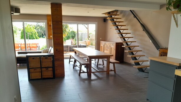 Una cocina amplia con una mesa y banco de madera, una escalera y vistas al exterior.