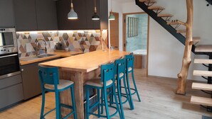 Una cocina moderna con una isla de madera, taburetes de bar azules y un salpicadero geométrico.