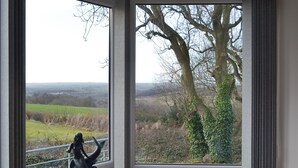 Une pièce dotée de grandes fenêtres donnant sur un arbre et un paysage.