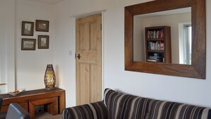 Un salon avec une porte en bois, une bibliothèque, un canapé à rayures et des tableaux encadrés accrochés au mur.