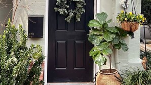 A house with a black front door, a wreath, and hanging flower baskets.