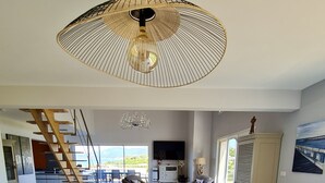 En rummelig spiseplads med et marmorbord, moderne stole, en stor ventilator i loftet og udsigt til det fri.