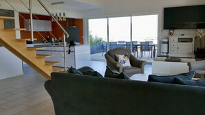 En moderne stue med trappe, spiseområde og køkken.