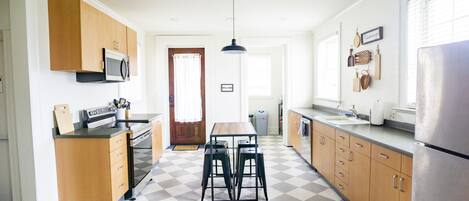 A kitchen with a checkered floor, wooden cabinets, a microwave, a sink, and a refrigerator.