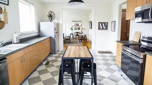 A kitchen with wooden cabinets, a black countertop, a central island with stools, a refrigerator, and a microwave.