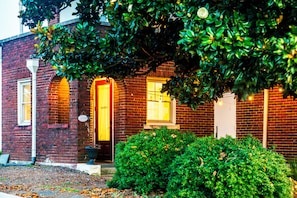 A brick building with a sign reading 'GUESTS' above the door, a small porch, and a well-maintained hedge in front. - Historic 1915 2BR · No Pet Fees (Chattanooga)