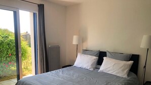 Une chambre avec un grand lit, deux lampes de chevet et une vue sur la verdure grâce à une porte coulissante.