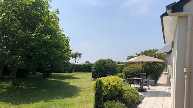 Un jardin bien entretenu, agrémenté d’une terrasse avec des meubles d’extérieur et un espace salon abrité.