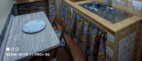 Een koelkast, een kookplaat, kookgerei, borden en bestek