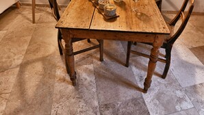 A wooden dining table with six chairs, a lamp, and a bottle on the table.